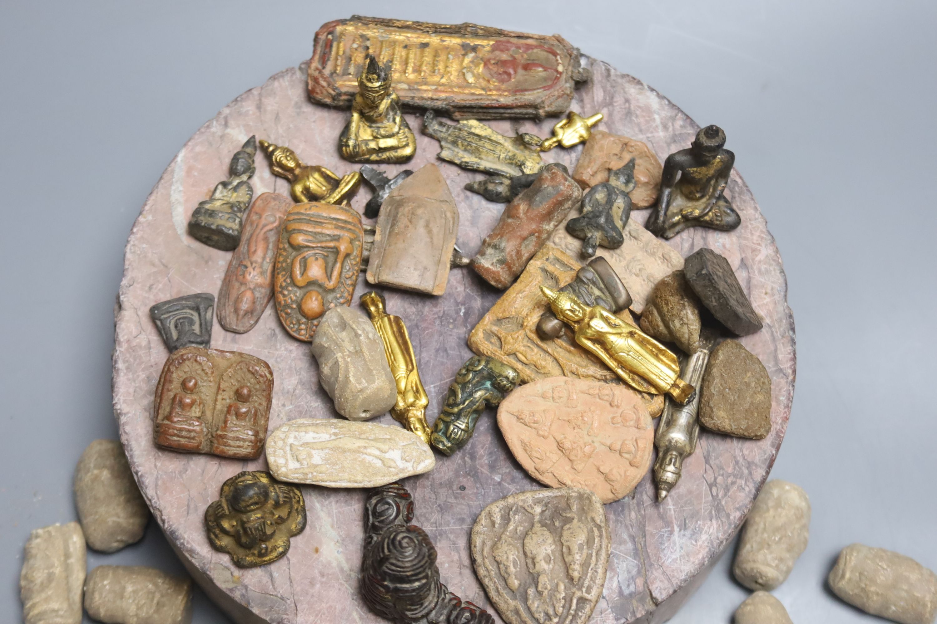 A rouge marble plinth and various Indian amulets